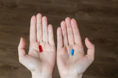 Kırmızı ve mavi hap kadın elinde.