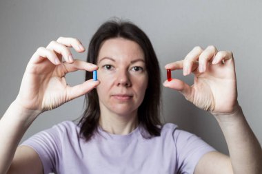 Kırmızı ve mavi hap kadın elinde.