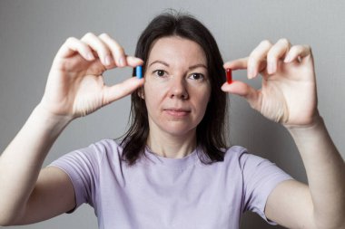 Kırmızı ve mavi hap kadın elinde.