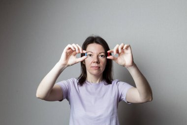 Kırmızı ve mavi hap kadın elinde.