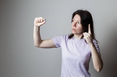 Elinde kırmızı bir hap tutan kız.