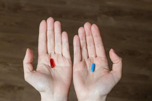 Red and blue pills in woman hands.