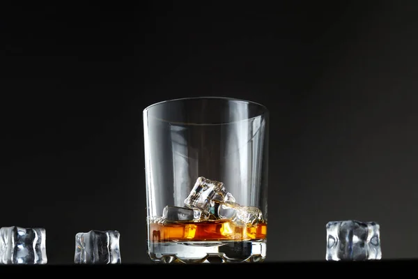暗い背景に氷のあるウイスキーのグラス ウイスキーと氷のグラスをテーブルの上に置いて — ストック写真
