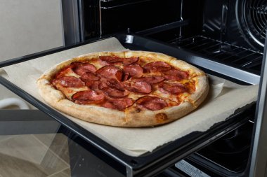 freshly baked pepperoni pizza on a baking sheet. Pizza taken out of the oven