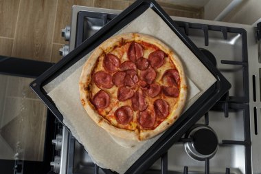 Fırında yeni pişmiş pizza ve kabartma kağıdı. Fırının üstünde pizzalı bir çarşaf var.