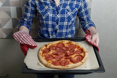 girl holding a freshly baked pizza.