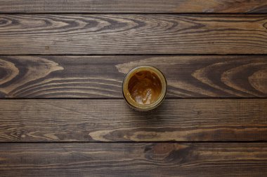 Tahta bir masada kavanozda fıstık ezmesi.