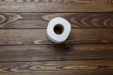 Tuvalet kağıdı ahşap arka planda yuvarlanıyor.