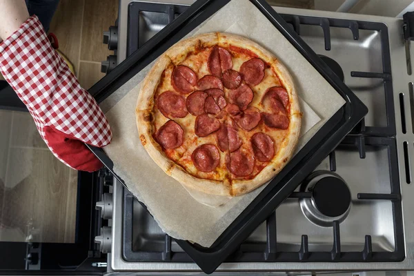 Fırında yeni pişmiş pizza ve kabartma kağıdı. Fırının üstünde pizzalı bir çarşaf var.