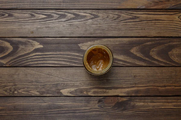 Tahta bir masada kavanozda fıstık ezmesi.