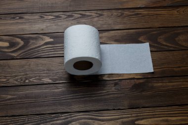 Tuvalet kağıdı ahşap arka planda yuvarlanıyor.