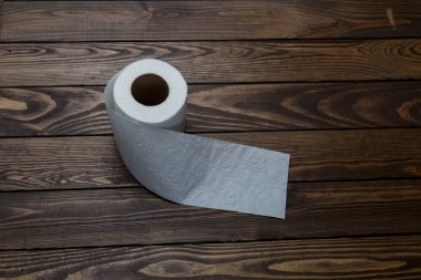 Tuvalet kağıdı ahşap arka planda yuvarlanıyor.