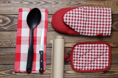 Mutfak aletleri konsepti. Tutacağı, fırın kağıdı, fırın kağıdı ve ahşap bir arka planda bir kepçe..