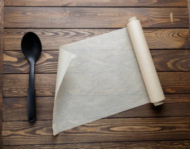 Masanın üzerinde kaşık ve kağıt var. Ahşap bir arka planda kağıt yapmak. Bir rulo kağıt açıyorum..