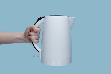 Mavi arka planda elektrikli su ısıtıcısı tutan kız..