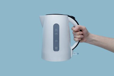 Mavi arka planda elektrikli su ısıtıcısı tutan kız..