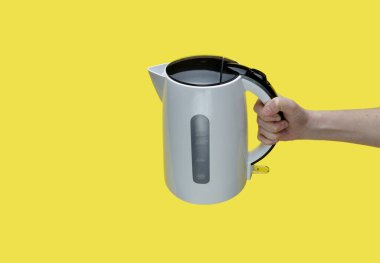 Sarı arka planda elektrikli su ısıtıcısı tutan kız..