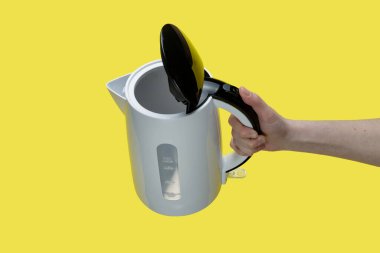 Sarı arka planda elektrikli su ısıtıcısı tutan kız..