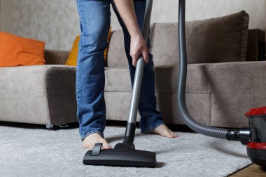 Kot pantolonlu bir adam süpürge yapıyor. Ev temizliği