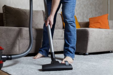 Kot pantolonlu bir adam süpürge yapıyor. Ev temizliği