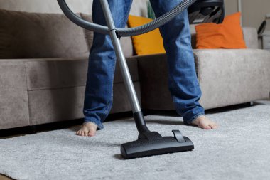 Kot pantolonlu bir adam süpürge yapıyor. Ev temizliği