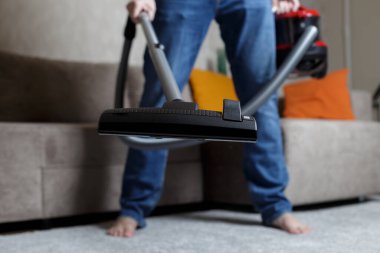 a man in jeans is vacuuming. House cleaning