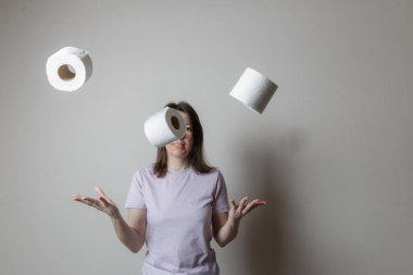 toilet paper concept. beautiful girl in a good mood, smiling, throwing up a lot of toilet paper rolls, has a happy look, has fun