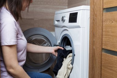 Çamaşır yıkama kavramı. Kız çamaşır makinesini yüklüyor..