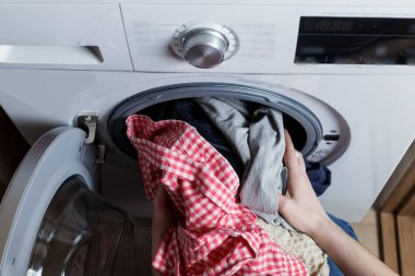 laundry washing concept. the girl is loading the washing machine.