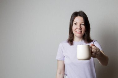 Kız elinde bir fincan çay tutuyor. Kız güzel gülümsüyor.