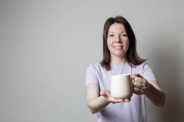 Kız elinde bir fincan çay tutuyor. Kız güzel gülümsüyor.