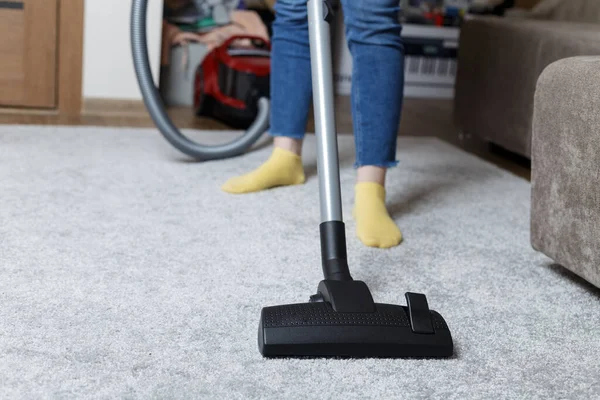 Een Meisje Een Blauwe Spijkerbroek Stofzuigt Het Tapijt Huisreiniging — Stockfoto