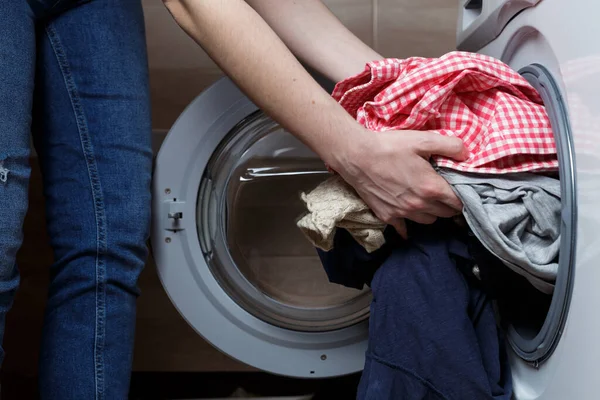 laundry washing concept. the girl is loading the washing machine.