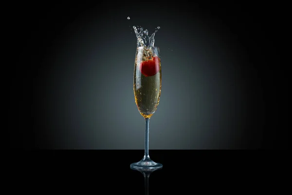 動きを捉えました シャンパンのスプラッシュと暗い背景に落ちるイチゴ — ストック写真