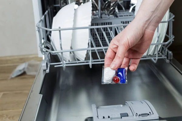 girl loads a tablet into the dishwasher. girl washes dishes in the dishwasher.
