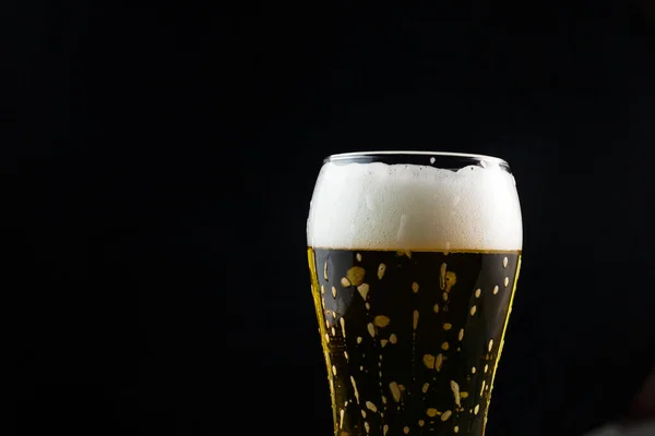 beer in a glass on a dark background. beer foam flows down the walls of the glass