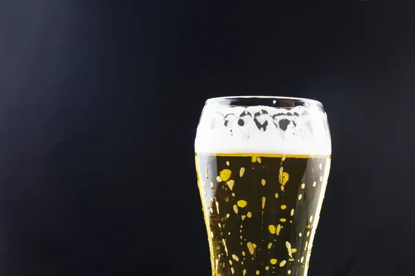 beer in a glass on a dark background. beer foam flows down the walls of the glass