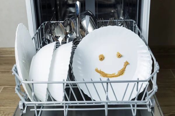 perfectly washed dishes in the dishwasher. Joyful smile on a plate