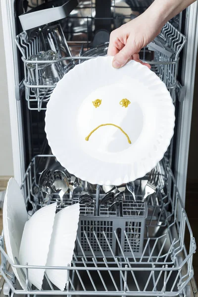 poorly washed dishes in the dishwasher. hand holds a plate depicting sad emotion