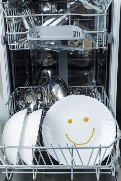 well-washed dishes in the dishwasher. a happy emotion is depicted on a plate