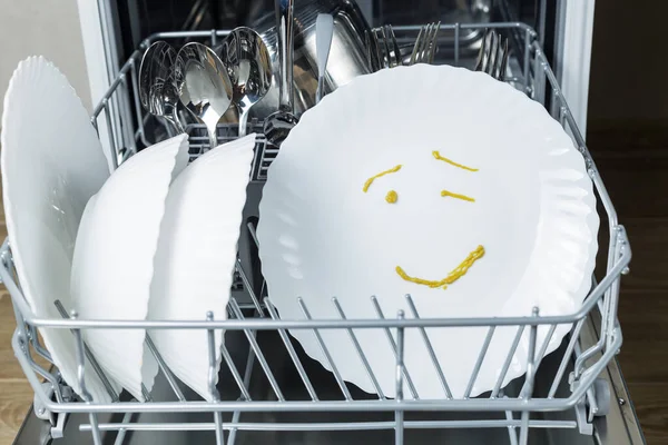 well-washed dishes in the dishwasher. a winking emotion is depicted on a plate