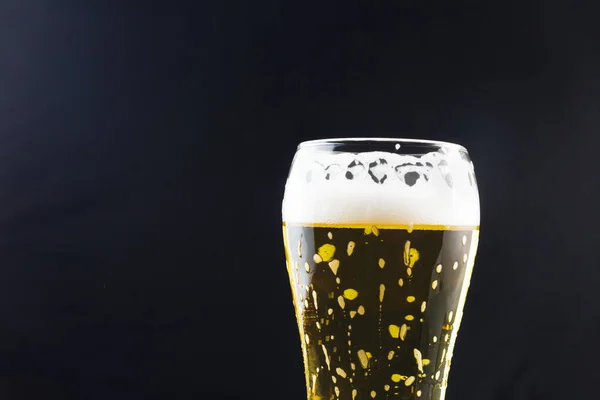 beer in a glass on a dark background. beer foam flows down the walls of the glass