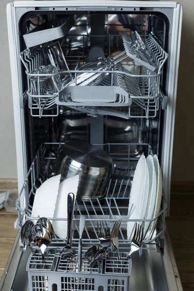 dishwasher with dishes. loaded dishwasher. plates, knives, spoons and forks are well washed. vertical photo