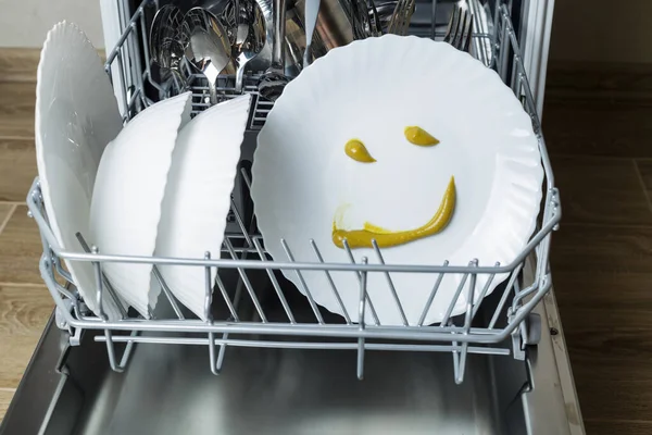 perfectly washed dishes in the dishwasher. Joyful smile on a plate