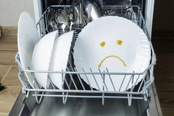 poorly washed dishes in the dishwasher. the plate depicts a sad emotion