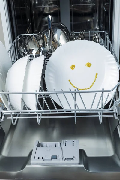 well-washed dishes in the dishwasher. a happy emotion is depicted on a plate