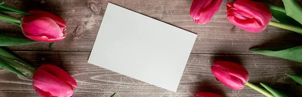 Tulipanes rosados y tarjeta de regalo sobre fondo de madera. Espacio para el texto. Vista superior — Foto de Stock