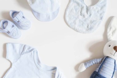 Yeni doğmuş bebek kıyafetleri ve beyaz arka planda tavşan oyuncağı, Üst manzara, düz yatış.