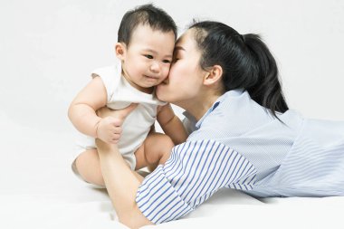 Selective focus Beautiful mom kissing on the cheek newborn with love and caring, Mother showing love to toddler with kiss on cheek.