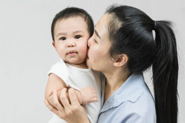 Selective focus Beautiful mom kissing on the cheek newborn with love and caring, Mother showing love to toddler with kiss on cheek.
